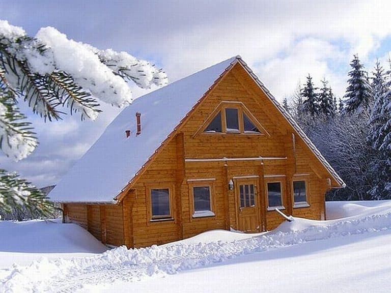 Eine mit Schnee und Kiefern bedeckte Holzhütte in Nordrhein-Westfalen.