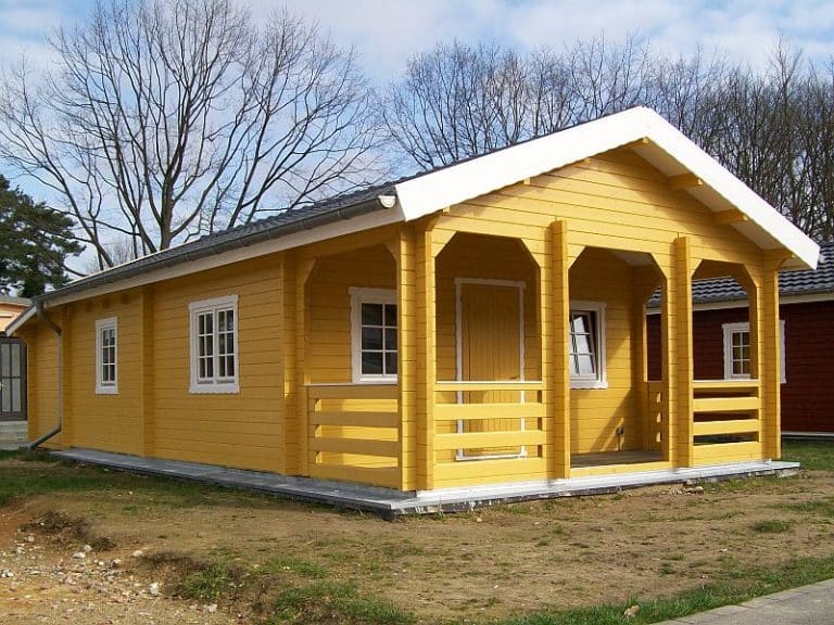 Ein kleines gelbes Ferienhaus mit weißer Veranda.