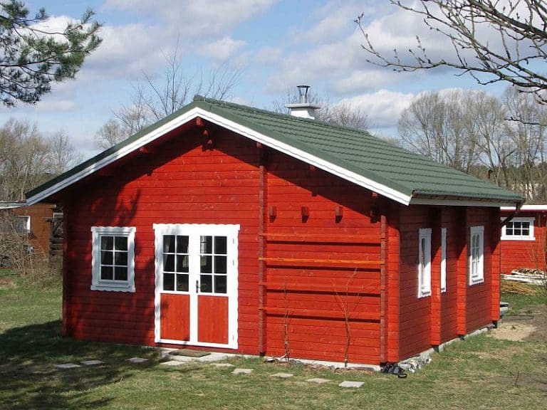 Ein rotes Blockbohlen-Holzhaus mit grünem Dach in Baden-Württemberg.