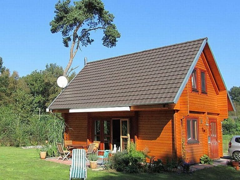 Ein gemütliches Ferienhaus inmitten einer schleswig-holsteinischen Wiese aus Blockbohlen.