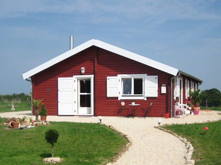 Ein rotes Ferienhaus mit weißen Fensterläden und einem Weg.