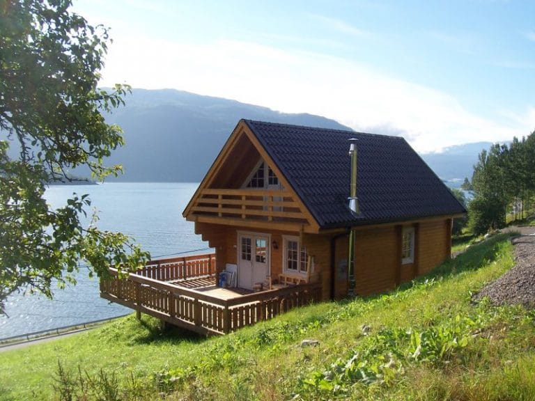 In Mecklenburg-Vorpommern liegt ein Blockbohlen-Ferienhaus auf einem Hügel neben einem See.