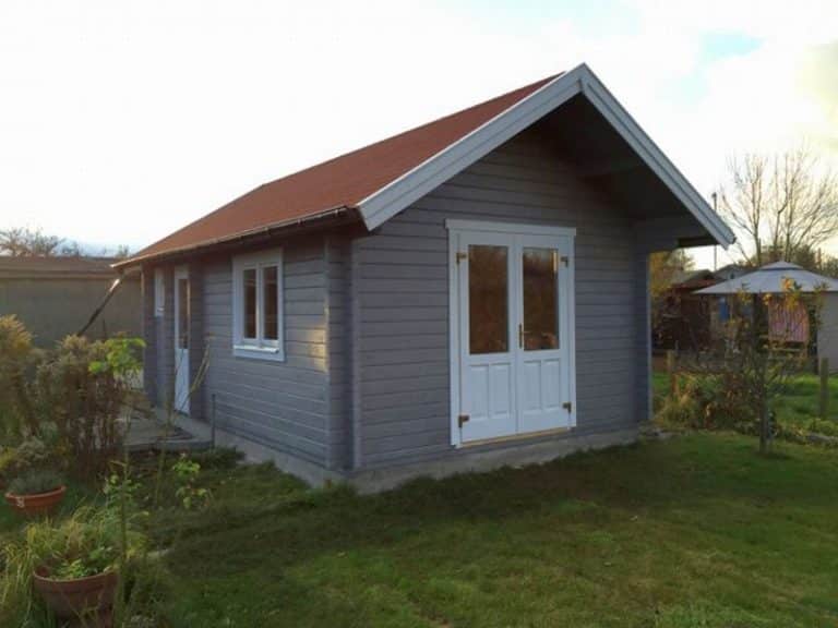 Ein kleiner Schuppen in einem Garten mit rotem Dach.